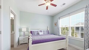 A bedroom with a bed, nightstand, window, and ceiling fan. - Flamingo Hideaway Modern House w Elevator (North Myrtle Beach)