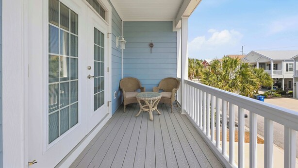 A covered porch with a table and chairs, a white railing, and a view of neighboring houses. - Flamingo Hideaway Modern House w Elevator (North Myrtle Beach)