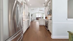 A kitchen with white cabinets, stainless steel appliances, and a wooden floor.