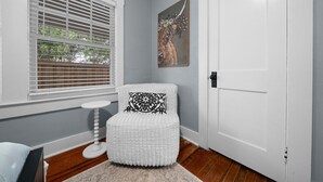 Une pièce avec une chaise blanche, une petite table ronde et une porte.