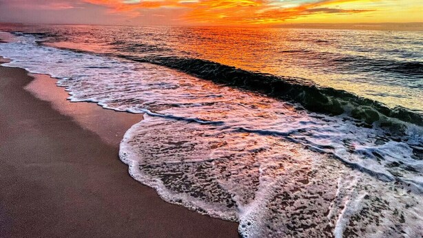 Une plage avec des vagues et un coucher de soleil.