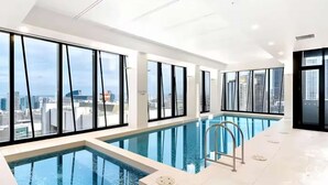 Ein moderner, überdachter Pool mit großen Fenstern und Blick auf die Stadt.