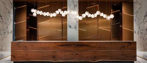 A reception area with a wooden reception desk, marble walls, and a geometric patterned floor.