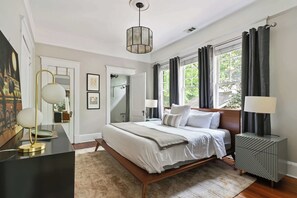 Quarto moderno com uma cama grande, abajures, mesa de cabeceira e vista para o verde lá fora.