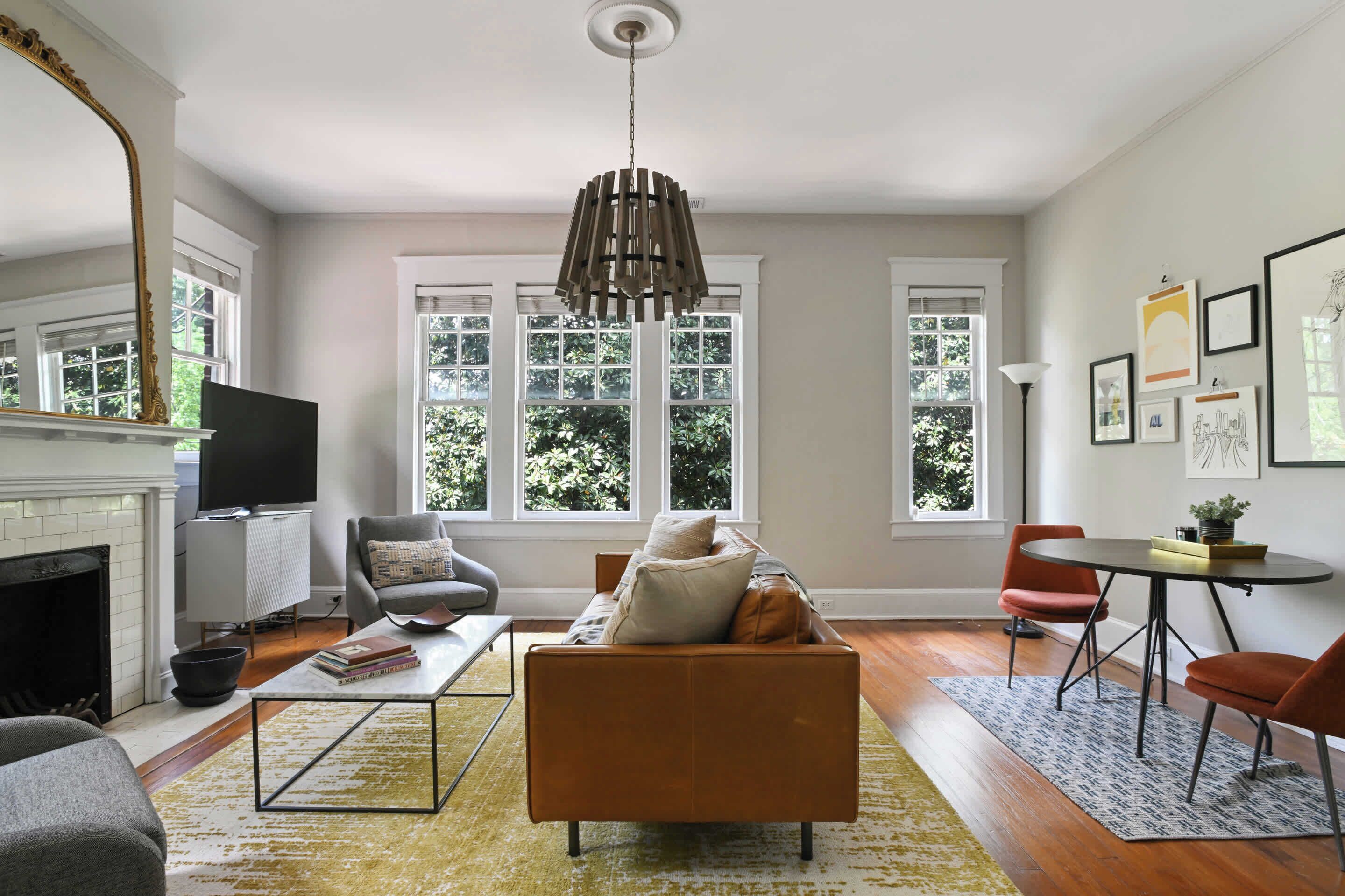 A spacious living room with a fireplace, a large window, and a modern chandelier.
