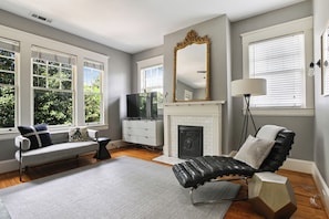 A living room with a fireplace, a sofa, a black leather chair, and a large mirror.