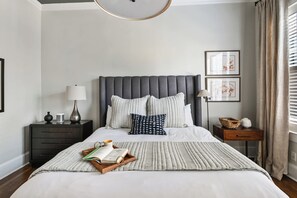 A neatly arranged bedroom with a large bed, bedside tables, and a bedside lamp.