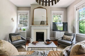 A living room with two armchairs, a fireplace, a television, and a large mirror.