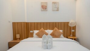 A neatly made bed with a wooden headboard, a bedside table with a lamp, and two wall art pieces. - Ongsa Poolvilla Udonthani (Udon Thani)