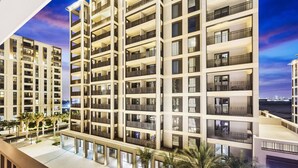 A multi-story hotel with balconies, a rooftop terrace, and palm trees.