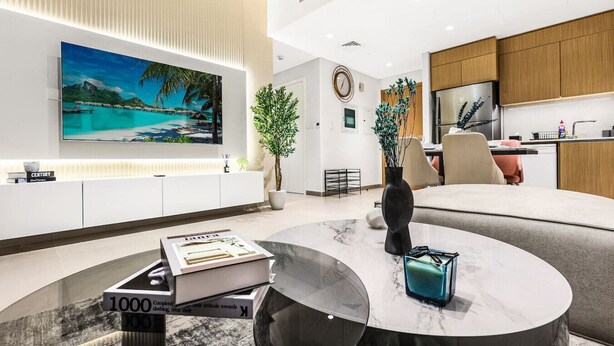 A modern living room with a large flat-screen TV, a marble coffee table, and a comfortable sofa.