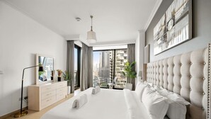Une chambre moderne avec un grand lit, une commode, un miroir et une vue sur la ville.