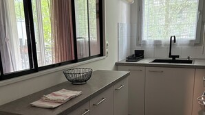 A modern kitchen with a large window, a sink, and a countertop. - Charming T2 on the edge of the Seine with terrace (Mantes-la-Jolie)