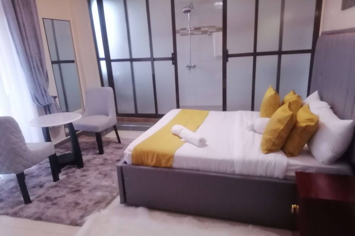 Een hotelkamer met een bed, een stoel, een klein tafeltje en een spiegel.