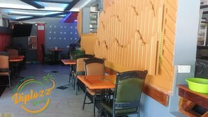 Un interior de restaurante con varias mesas y sillas, una pared decorativa de madera y un logotipo en el suelo.
