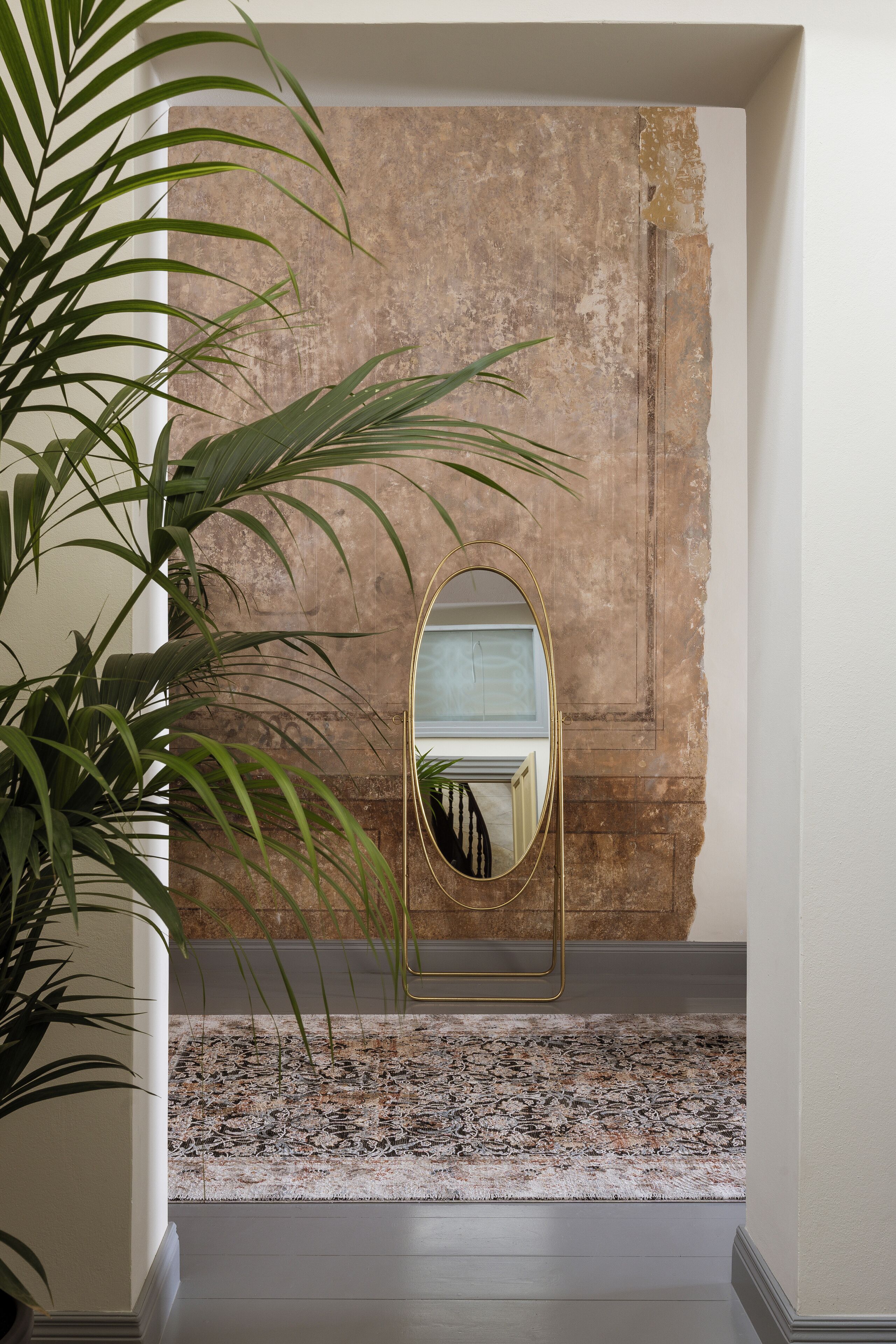Un couloir avec un grand miroir, un mur à motifs et un tapis décoré.