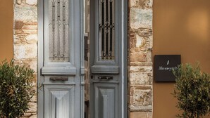 A double door with intricate metalwork, set in a stone and brick facade, with a sign above indicating the name "Alnasys." - Alma Syros (Syros)
