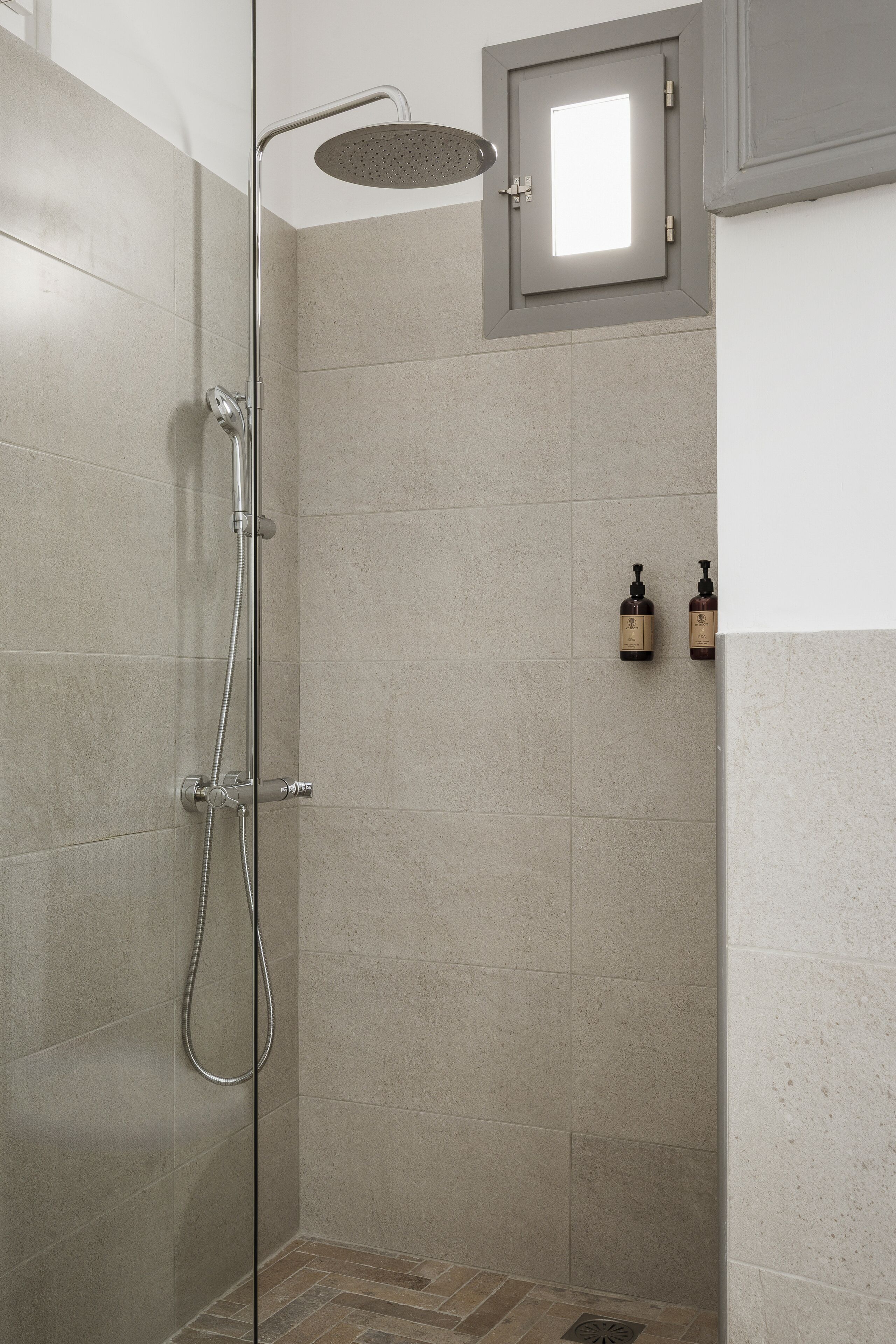 A shower with a handheld showerhead and a wall-mounted control panel.