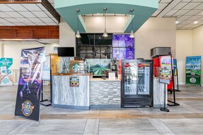 A coffee shop counter with a menu board, a refrigerator, and a promotional stand.