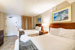 A hotel room with two beds, a wooden headboard, a nightstand with a lamp, a door with a handle, and a framed picture on the wall. - Oceanview Condo, Pool, Steps to Beach, Hot Tubs (Myrtle Beach)