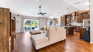 Ein geräumiges Wohnzimmer mit einer großen Couch, Holzschränken und einer Küchenzeile mit modernen Geräten.