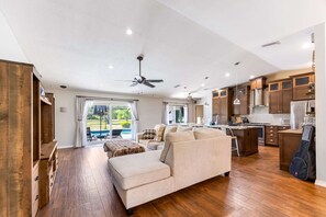 A spacious living room with a large sofa, wooden cabinets, and a kitchen area with modern appliances. - 3BR Wesley Chapel Retreat with Private Pool • Pet-Friendly • Spacious Parking (Zephyrhills)