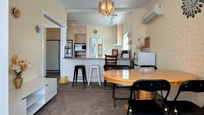 A compact kitchen with a dining area, white cabinetry, a chandelier, and a decorative wall clock. - Coleman Comfort Hub  - close to City&Air port (Moonah)