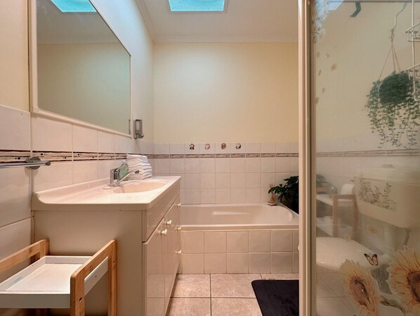 A bathroom with a sink, mirror, and bathtub.