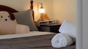 A bed with a large plush toy, a lamp, a stack of books, and a rolled towel. - Coleman Comfort Hub  - close to City&Air port (Moonah)