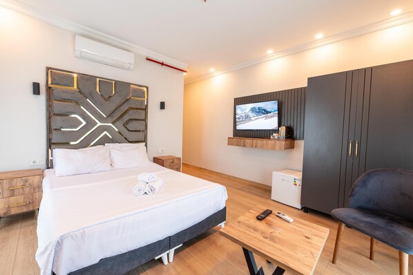 A modern hotel room with a large bed, a TV mounted on the wall, a wardrobe, and a small table with a remote control. - Highway 34 Hotel (Istanbul)