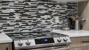 Uma cozinha moderna com fogão de aço inoxidável, relógio digital e backsplash de azulejos preto e branco.