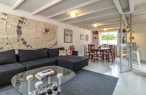 Una sala de estar moderna con un sofá modular, una mesa de centro de vidrio y un comedor con sillas de madera.