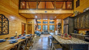 Interior espaiós d'una cabana de fusta amb menjador, cuina i sala d'estar.