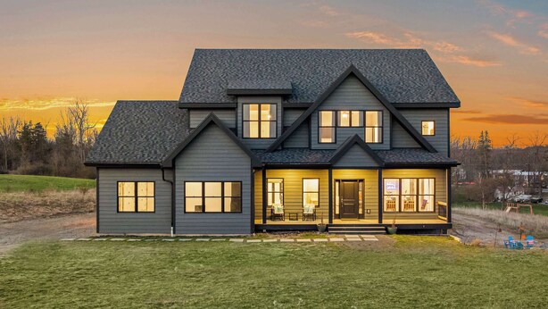 A two-story house with a front porch, large windows, and a dark roof. - The Silversands Lakehouse | Hot Tub • Sauna • Game Room (Lansing)