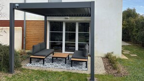 A covered patio area with a sofa and two tables, a sliding glass door, and a small window. - House in Fouras near Espérance beach  (Fouras)