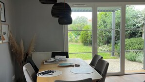 A modern dining area with a wooden table, grey upholstered chairs, and pendant lighting. - House in Fouras near Espérance beach  (Fouras)