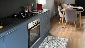 A modern kitchen with blue cabinets, a gas stove, and a dining area with a wooden table and chairs. - House in Fouras near Espérance beach  (Fouras)