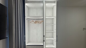 Un dressing moderne et vide, avec un téléviseur à écran plat fixé au mur, un luminaire au plafond et un sol carrelé.