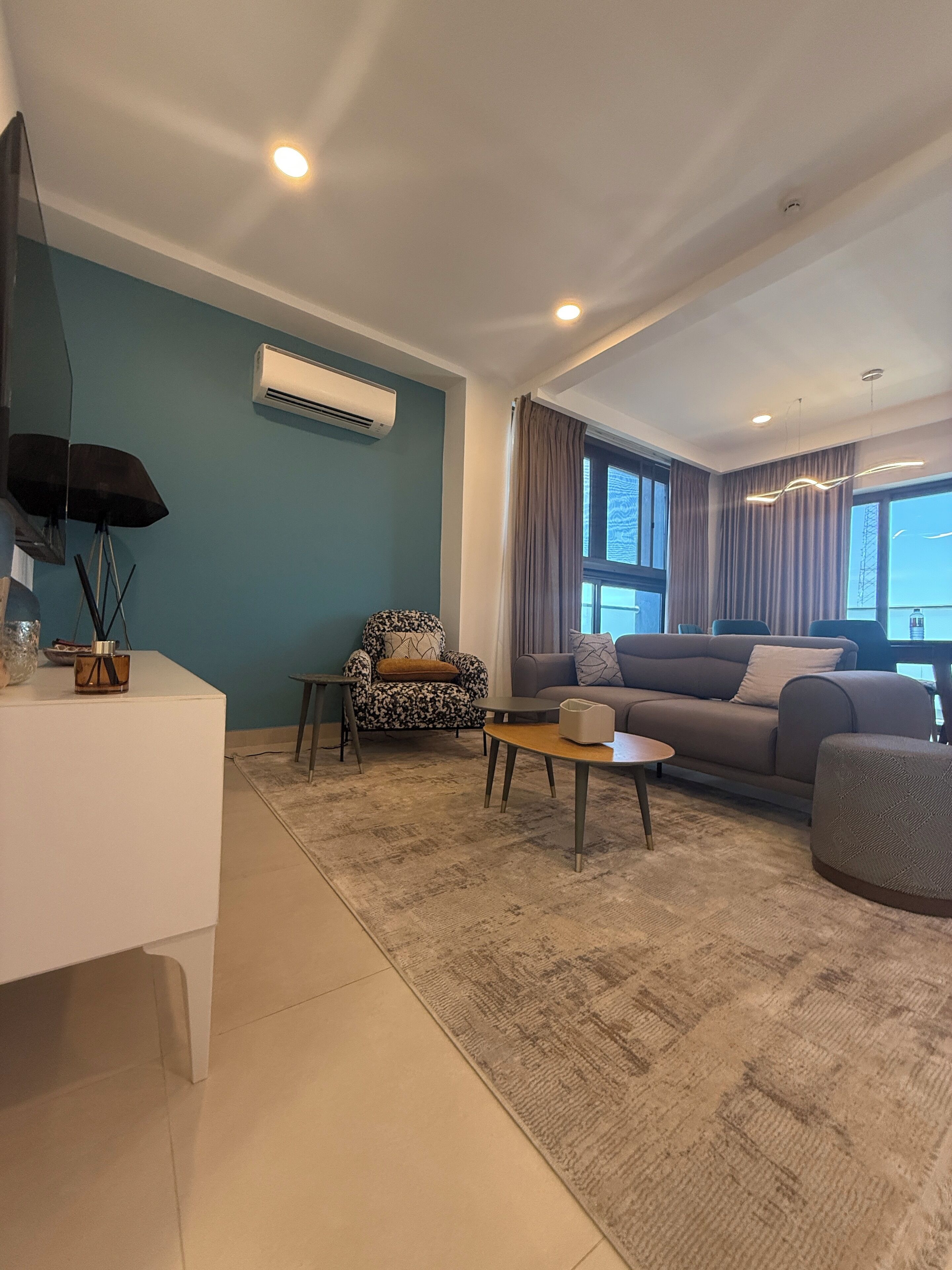 Una sala de estar moderna con sofá, sillón, mesa de centro y televisor de pantalla plana.