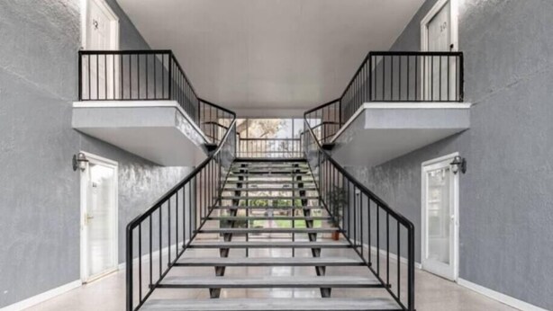Una escalera con barandillas metálicas que lleva a un rellano con una puerta.