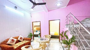 A room with a sofa, two wicker chairs, a small table, and a staircase. - Hotel The Premium Villa Rishikesh (Uttarakhand)
