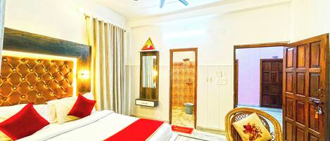 A hotel room with a bed, a mirror, a ceiling fan, and a bathroom door.