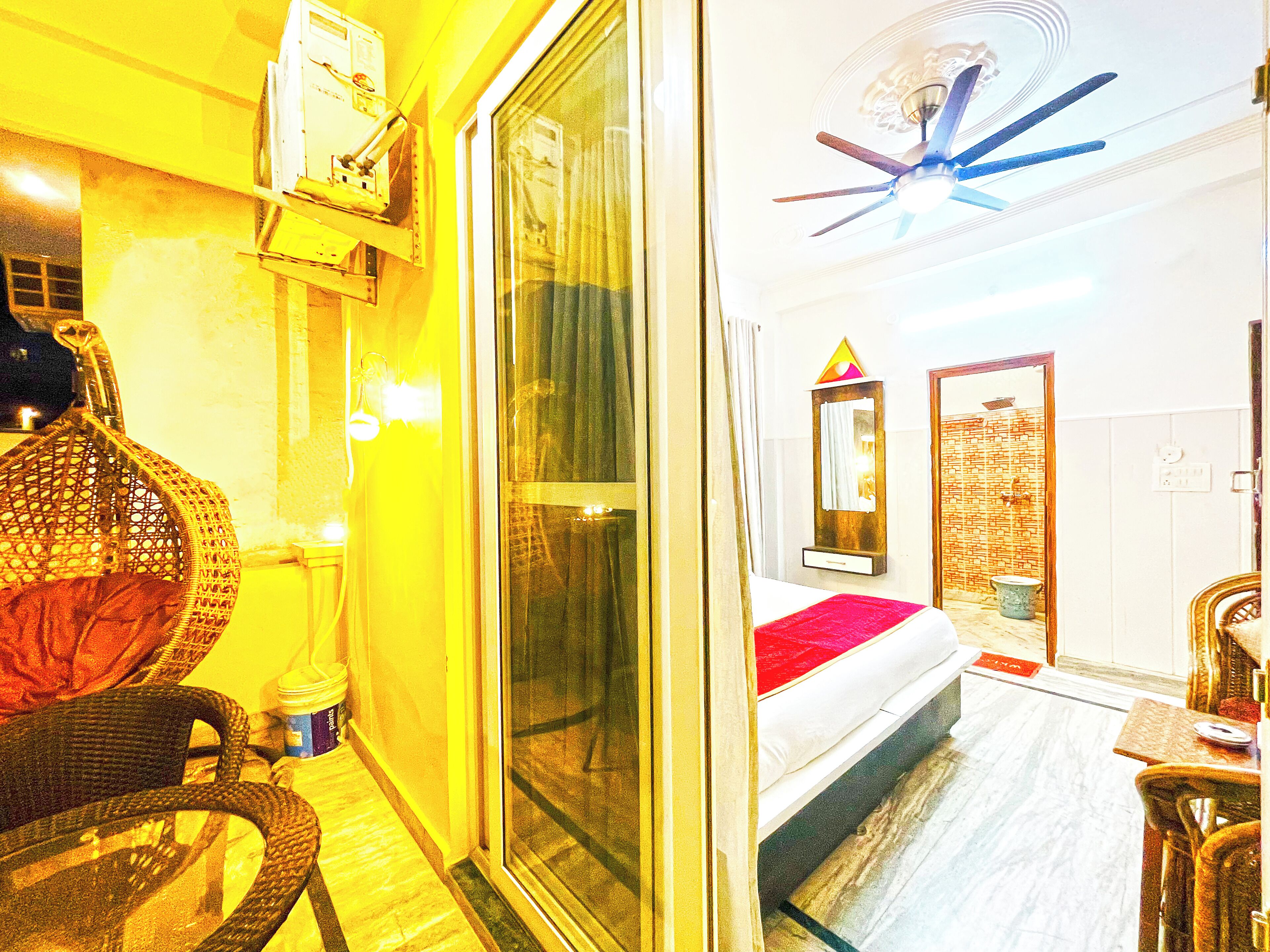 A hotel room with a bed, a ceiling fan, a window, and a small table with a chair.
