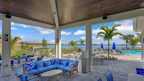 An outdoor patio with a pool, lounge chairs, and a blue sofa. - Wildblue - William Raveis Rentals (Ft. Myers)