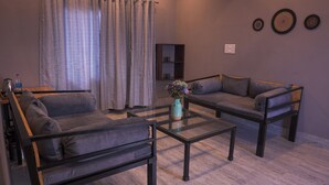 A living room with two sofas, a coffee table, a vase with flowers, a curtain, and wall decorations.