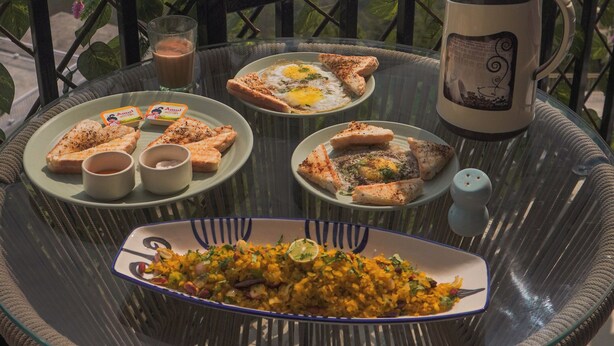 A table with food and a coffee pot on a balcony with a mountain view.