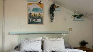 A bedroom with a bed, pillows, a wall-mounted shelf with plants, a poster, and a hanging plant. - Penthouse in somo near the beach. Lotus Flower - 30604 (Somo)