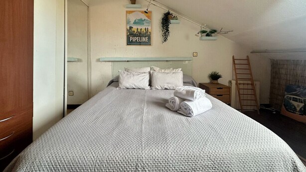 A neatly made bed with a patterned bedspread, a poster on the wall, and a ladder against the wall. - Penthouse in somo near the beach. Lotus Flower - 30604 (Somo)