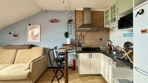 A compact kitchen with a dining area, a sofa, and a ceiling fan. - Penthouse in somo near the beach. Lotus Flower - 30604 (Somo)