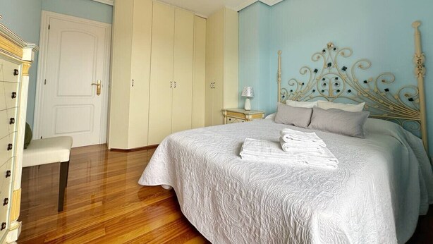 Un dormitorio con cama, mesita de noche, una silla y armario.